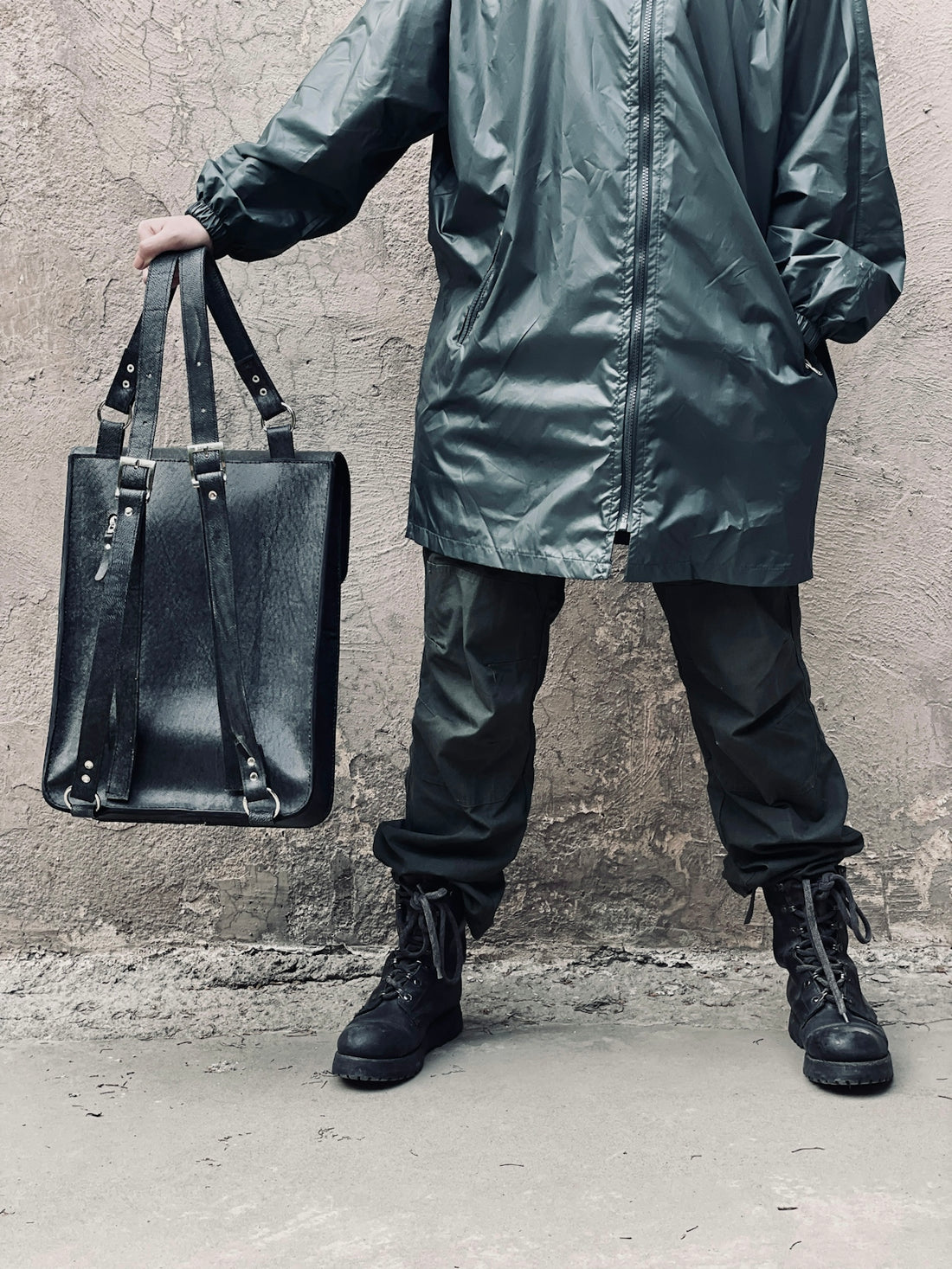 a man in a raincoat holding a black bag
